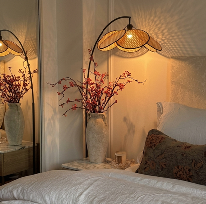 Modern rattan floor lamp with an arched metal stand and woven cane shade with wooden base.